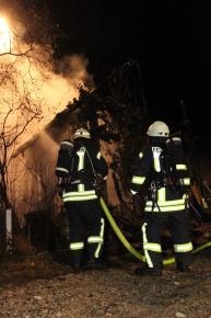 Zwei Feuerwehrleute löschen eine brennende Scheune