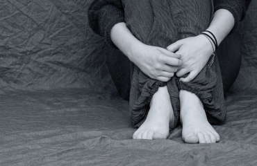 Schwarz-Weiß-Bild mit verschlossener Sitzposition einer Person 