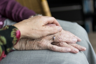 Seniorenhand wird von einer jüngeren Hand berührt 