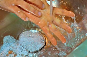 zwei Hände waschen sich unter fließendem Wasser
