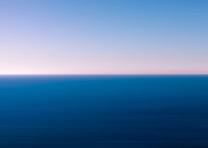 längs zweigeteiltes Bild: Oben blauer Himmel, unten dunkelblaues Wasser