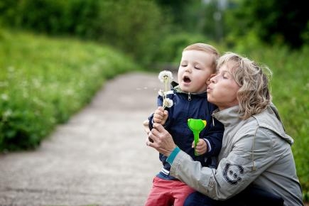 Blonde Frau mit Kind auf Weg mit Pusteblume.