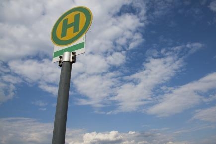 Schild Bushaltestelle vor blauem Himmel mit Wolken