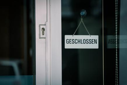 Symbolbild: geschlossene Glaseingangstüre mit Schild "geschlossen"