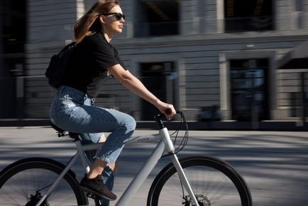 Symbolbild: Frau auf Fahrrad, im Hintergrund Gebäudekulisse.