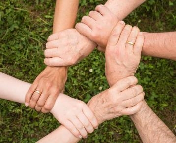 Gemeinsam Inklusion Mehrere Menschen legen ihre Hände übereinander. Das Bild soll Gemeinschaft, Zusammenarbeit und Inklusion.ion symbolisieren