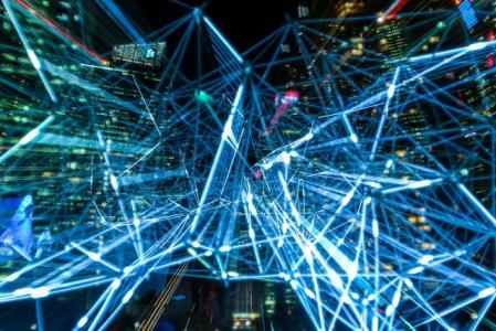 Hochhausschlucht bei Nacht, im Vordergrund neonfarbene Lichtströme
